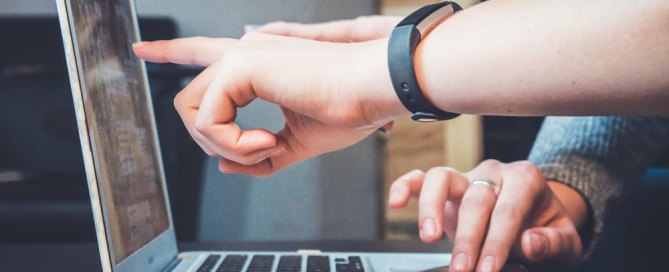 Two hands pointing at the monitor of a laptop