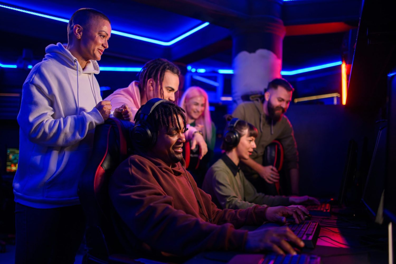 A group of young people sitting around a screen playing video games